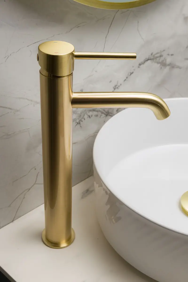 a bathroom sink with a gold faucet next to a white bowl